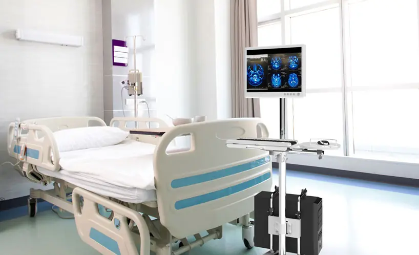 Mobile computer cart beside a hospital bed
