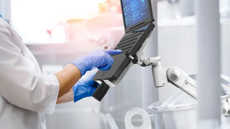 Gloved hand using a rugged laptop held by a mounting arm